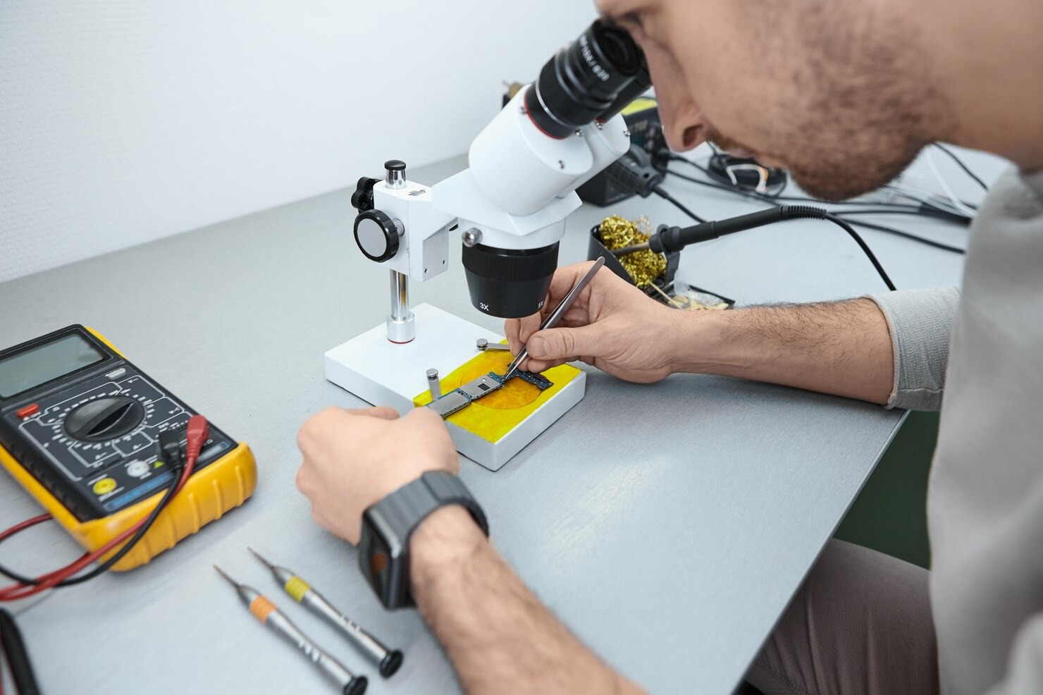 imgi_38_repairman-examining-mobile-phone-motherboard-microscope-laboratory_343059-499